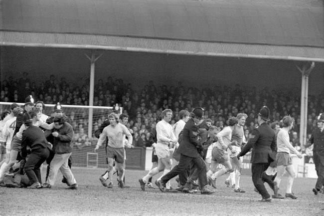 Policemen try to restore order after several Leeds United fans invaded the pitch, 1970s.