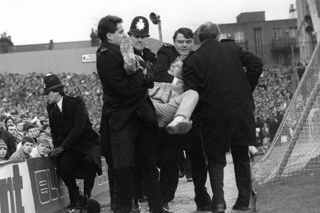 Police handle a fan who has been pulled out of the crowd, 1980s