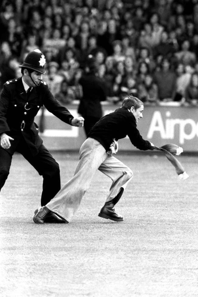 A Manchester United fan is chased by a policeman, 1970s.