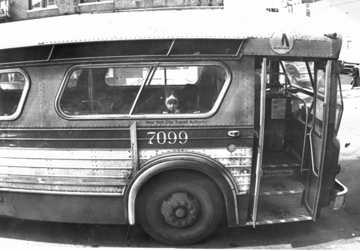 A child peering out of a bus window, 1977.