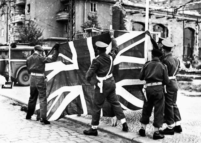 British Military Policemen hoist the Union Jack as the British Army enters Berlin, 1945.