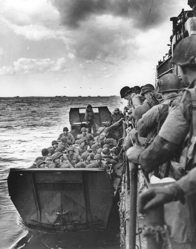 American assault forces hurtle over the side of a Coast Guard LCI into a landing barge, 1944.