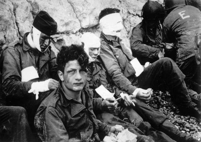 Men of the American assault troops of the 16th Infantry Regiment, injured while storming a coastal area code-named Omaha Beach, wait for evacuation, 1944.