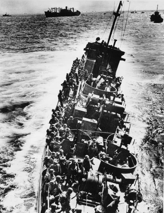 A U.S. Coast Guard LCI, heavily listing to port, moves alongside a transport ship, 1944.