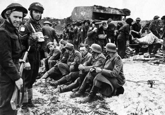 Canadian invasion troops stand guard over the first German prisoners captured, 1944.