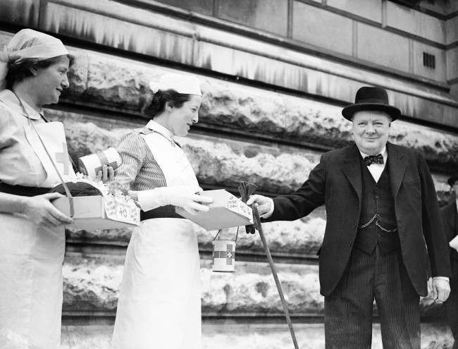 The Prime Minister, Winston Churchill, buying a Red Cross flag from a St. John’s Ambulance nurse, 1944.