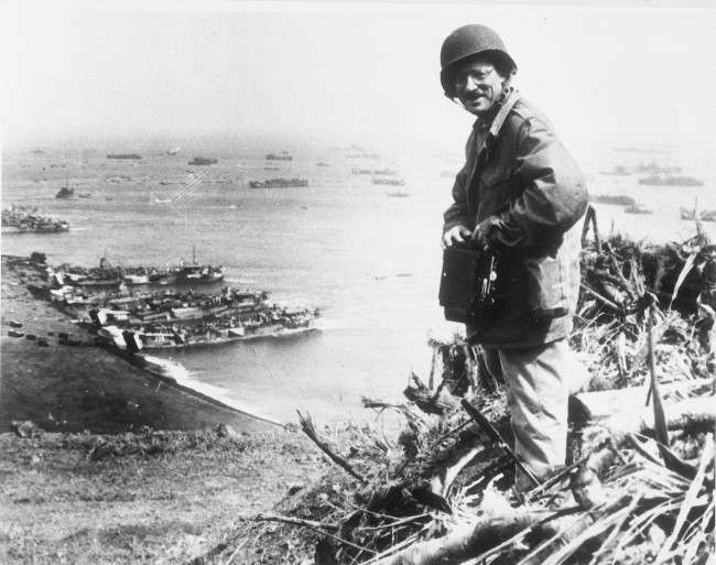 Joe Rosenthal, Associated Press photographer, is shown with his camera equipment looking over Iwo Jima. 1945