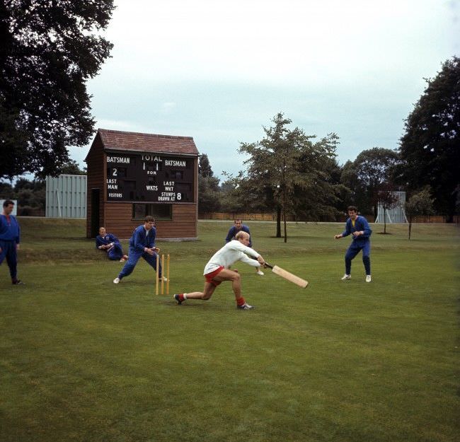 England’s Bobby Charlton (white shirt) wafts his bat at the ball, watched by (l-r) Terry Paine, Bobby Moore, Martin Peters, Gerry Byrne and Peter Bonetti, as the England squad relax with a game of cricket during a training session at Roehampton, 1966.