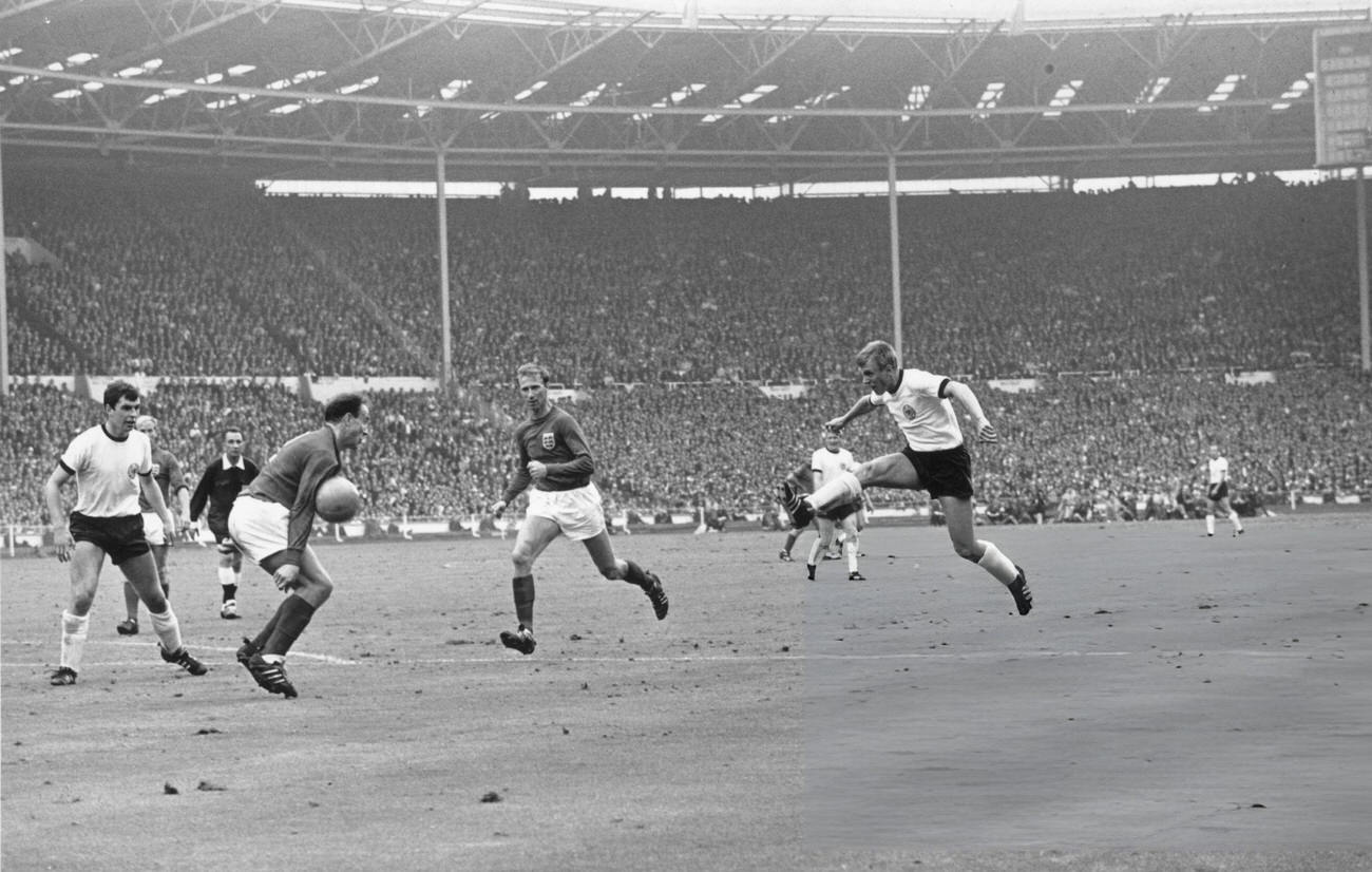 English footballer Jackie Charlton watches his teammate George Cohen block a shot, 1966.