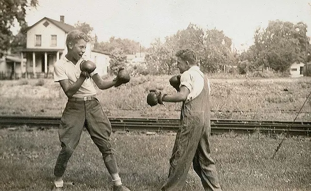 Young men boxing by the railroad tracks.