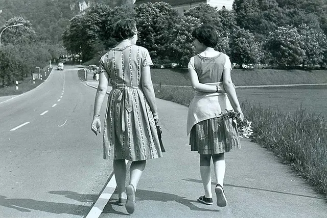 Two women walk with their backs to the camera.