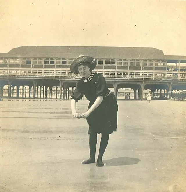 A homely girl wades in the ocean.