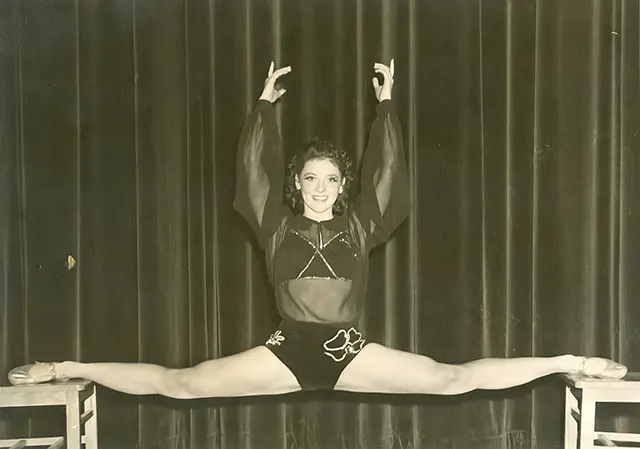 A circus acrobatic girl does a split.