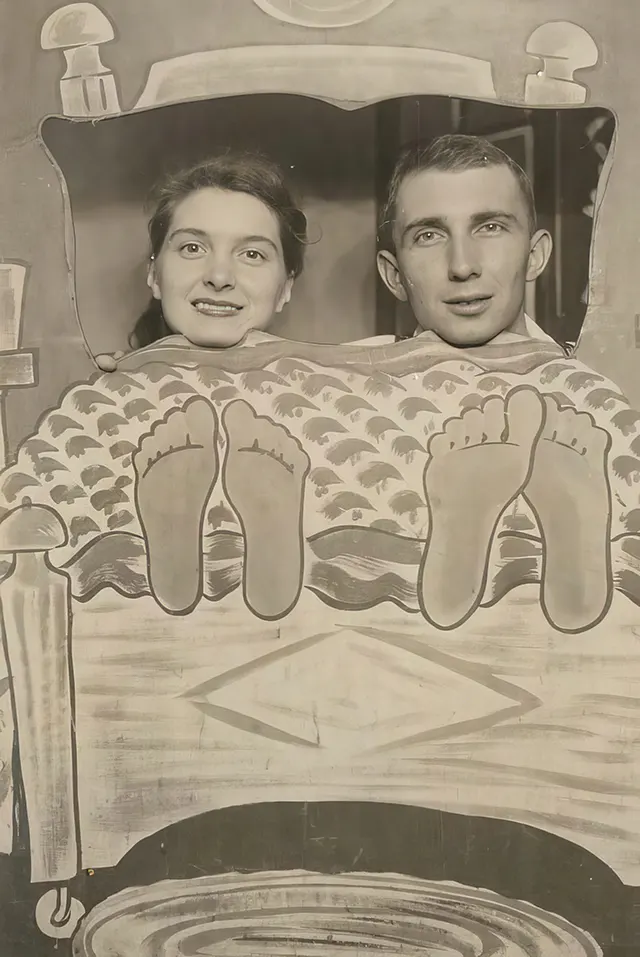 A couple poses with oversized feet in an arcade photo.