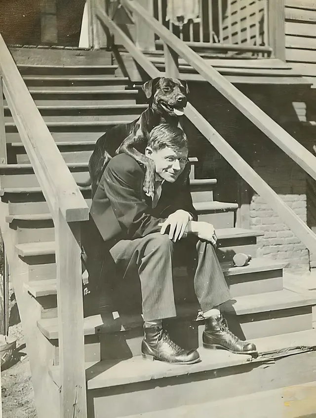 A dog poses with its owner on the steps.