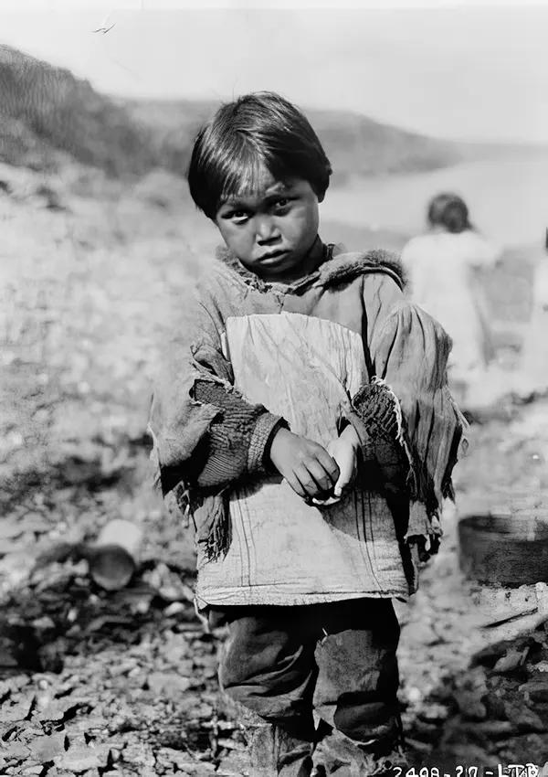 Eskimo boy wearing ragged clothing made from flour sacks, Belcher Islands, Northwest Territories, Canada, 1927.