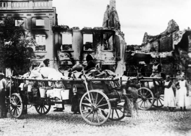 Civilians with their portable possessions loaded on wagons, in the ruins of a town destructed in the first sweep of the Czar’s armies into German territory.