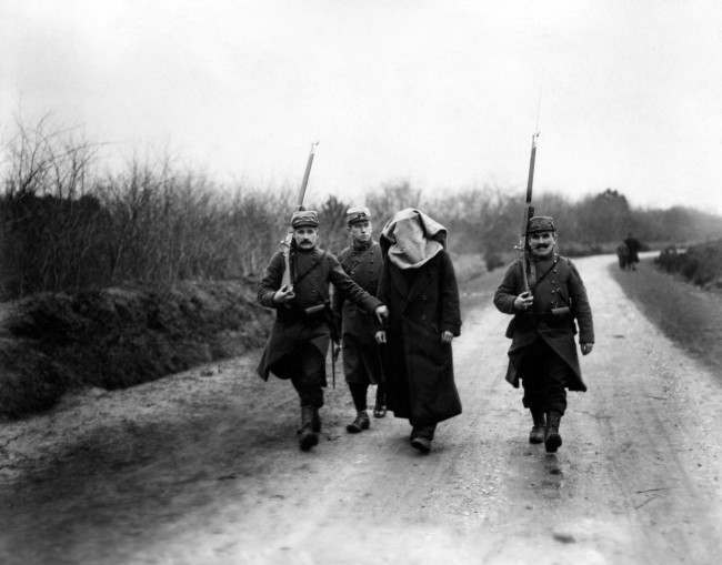 A blindfolded German prisoner is taken through the French lines.