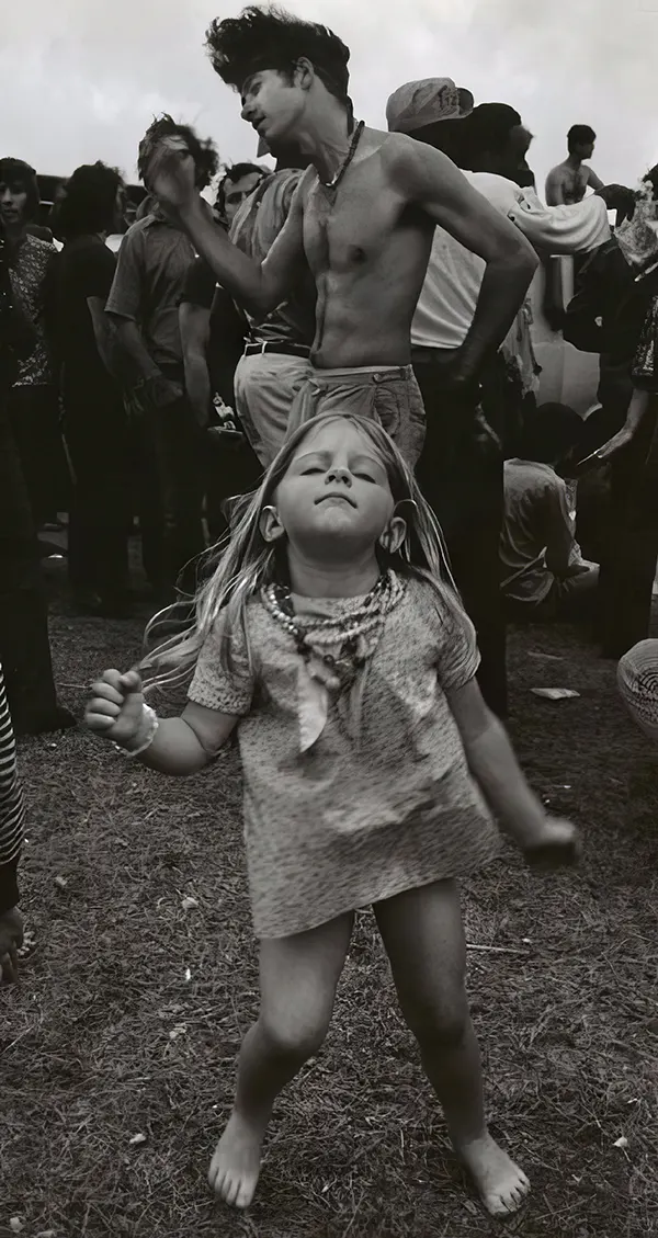 Little hippie girl going dance crazy at Woodstock, 1969.