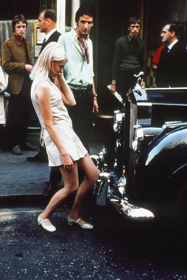 A beautiful girl admiring her reflection in a Rolls Royce while men around her get mesmerized, London, 1968.