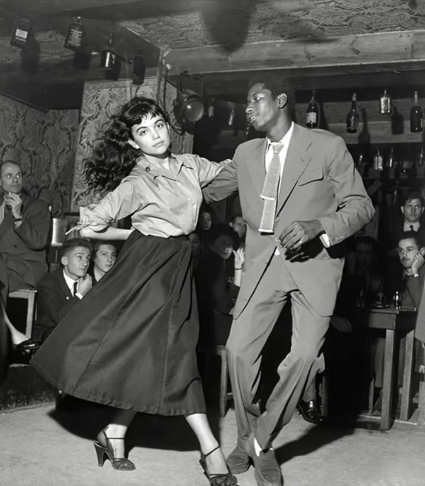 A couple dancing in a 1950s “Be Bop” theater as everyone looks on.