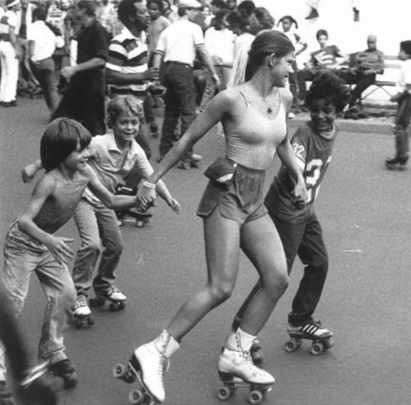 Pretty roller skating girls humor some boys at an Outdoor Roller Skating Rink, 1970s.