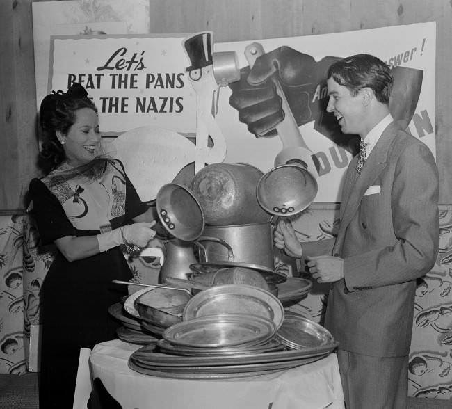 Merle Oberon, movie star, and Alfred G. Vanderbilt raise a din by beating pans at an aluminum-collection breakfast at the stork club in New York, July 23, 1941. The price of admission was a piece of aluminum ware.