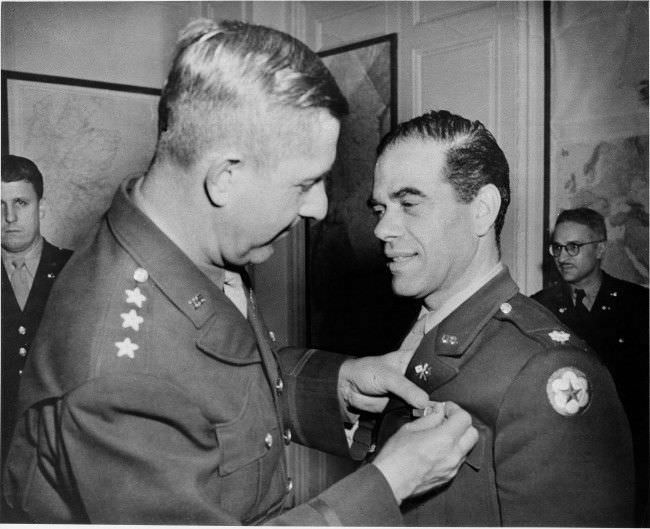 Lt. Gen. Jacob L. Devers, commander of U.S. forces in the European theater of operations, decorates Lt. Col. Frank Capra, former movie irector in Hollywood, now in the Signal Corps with the Legion of Merit Award, Nov. 29, 1943.