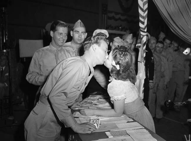 For the first time in her long movie career, Shirley Temple gets kissed in grown-up fashion by Jerry Shane, an ex-Marine from Grand Rapids, Mich., who plays a bit part in the movie called “Kiss and Tell,” Jan. 19, 1945.