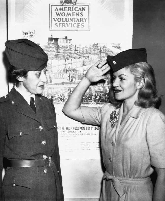 Mrs. Morton S. Stern (left) gets a salute from Claire Trevor after the movie actress had been inducted in the American womenÂs voluntary service in New York, Dec. 18, 1941.