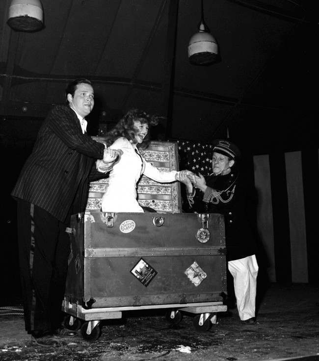 Soldiers cheered when Rita Hayworth, film star, was found again in a trunk, after Orson Welles, director-magician, had tied her in ropes and caused her to vanish on August 9, 1943 in Hollywood.