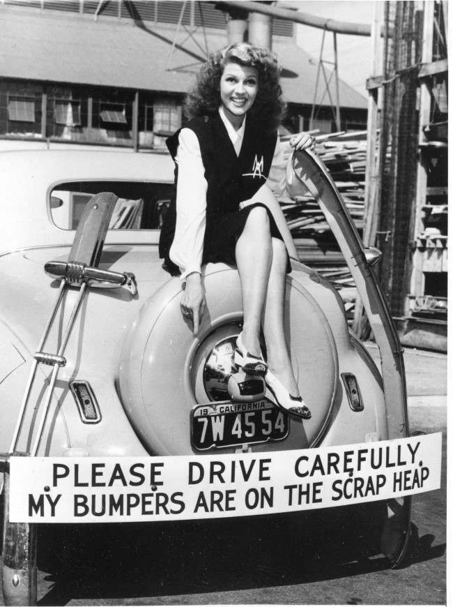 Actress Rita Hayworth participates in the scrap metal recycling campaign by donating her car’s bumper in response to the call for bumpers and other non-essential metal car parts for the war effort in Hollywood. Hayworth has also been selling war bonds.