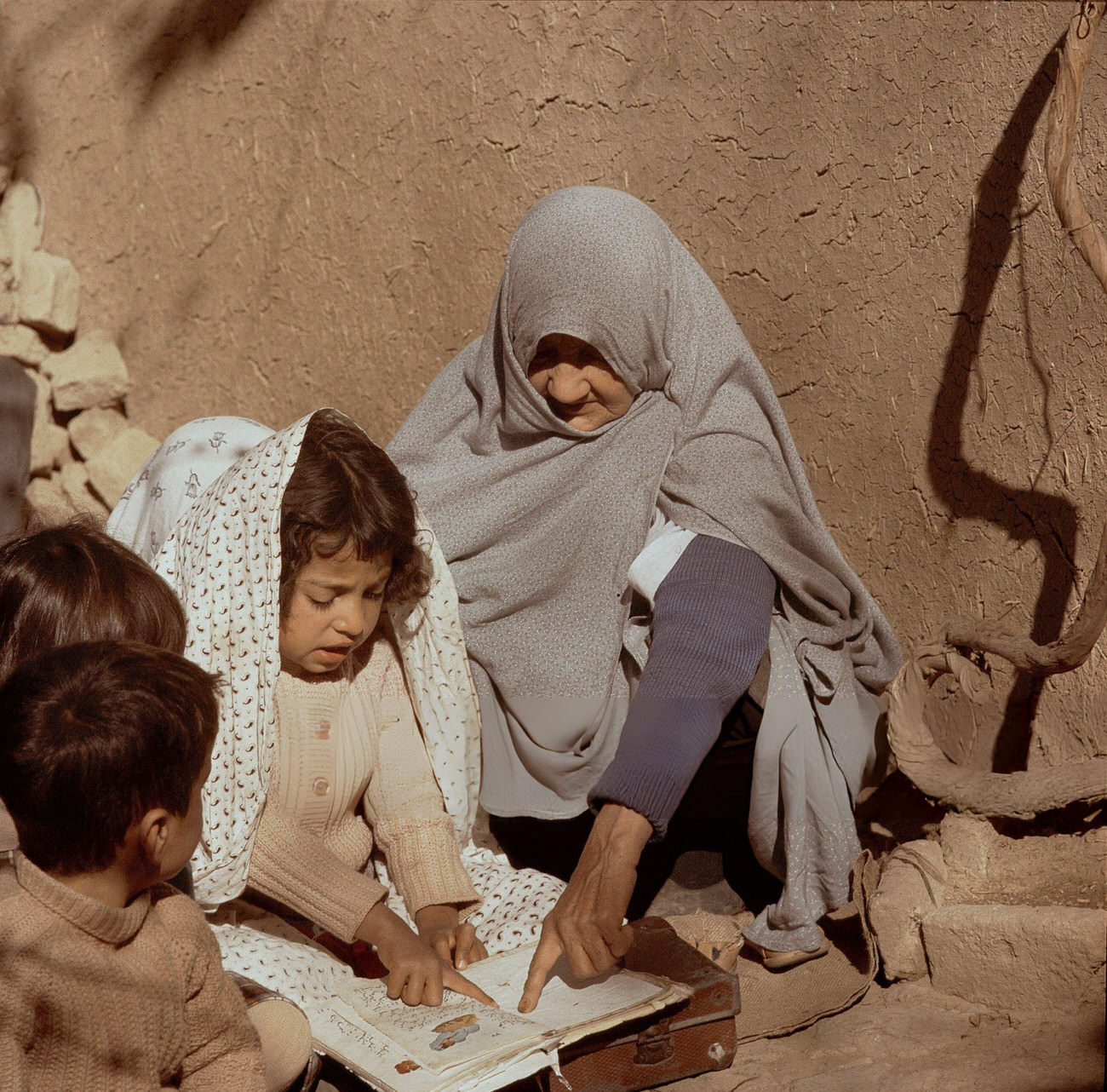 An elderly teacher instructs a girl how to read in a small village school in Iran, 1960s.