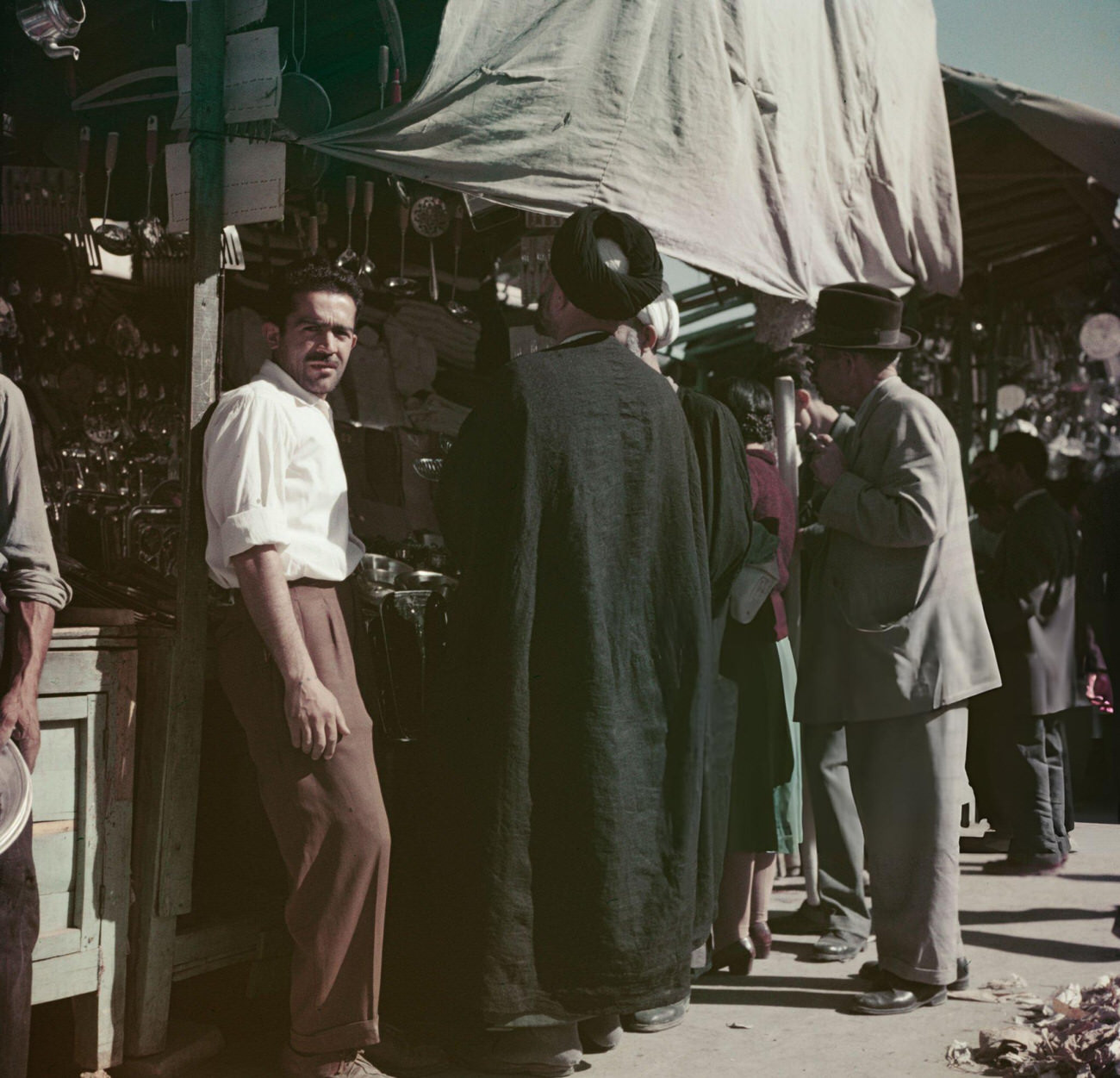 A mullah browsing goods for sale at a street bazaar in Tehran, the capital of Iran, circa 1960.