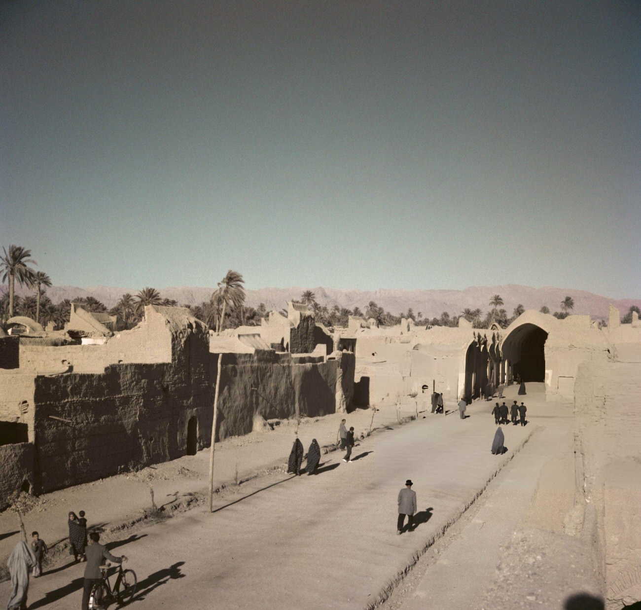 Pedestrians walking along a road in the oasis city of Tabas, formerly known as Golshan, in the province of South Khorasan in central Iran, circa 1960.