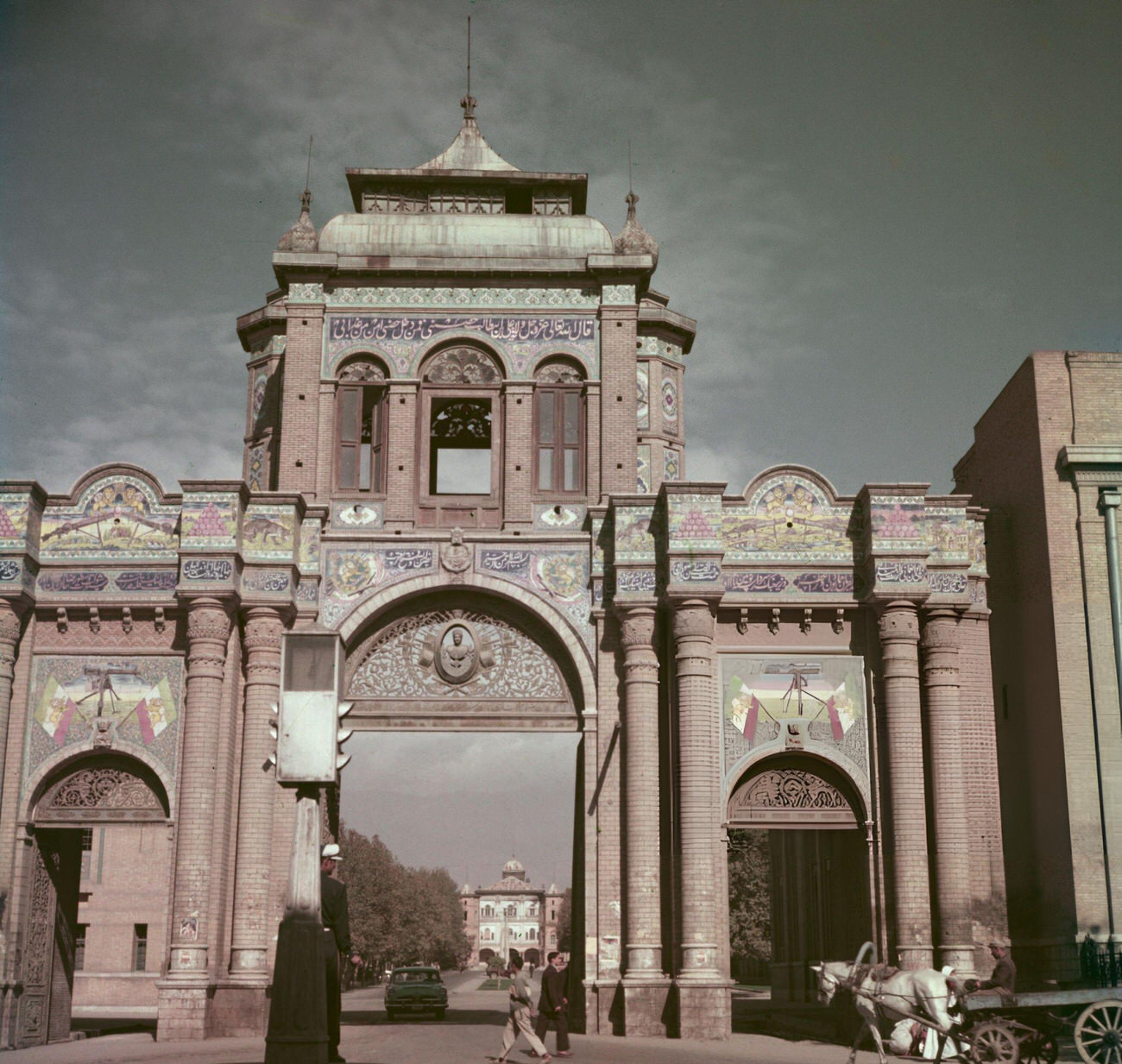 Pedestrians passing a decorative archway over a road leading to the Ministry of Defence building in Tehran, the capital of Iran, circa 1960.