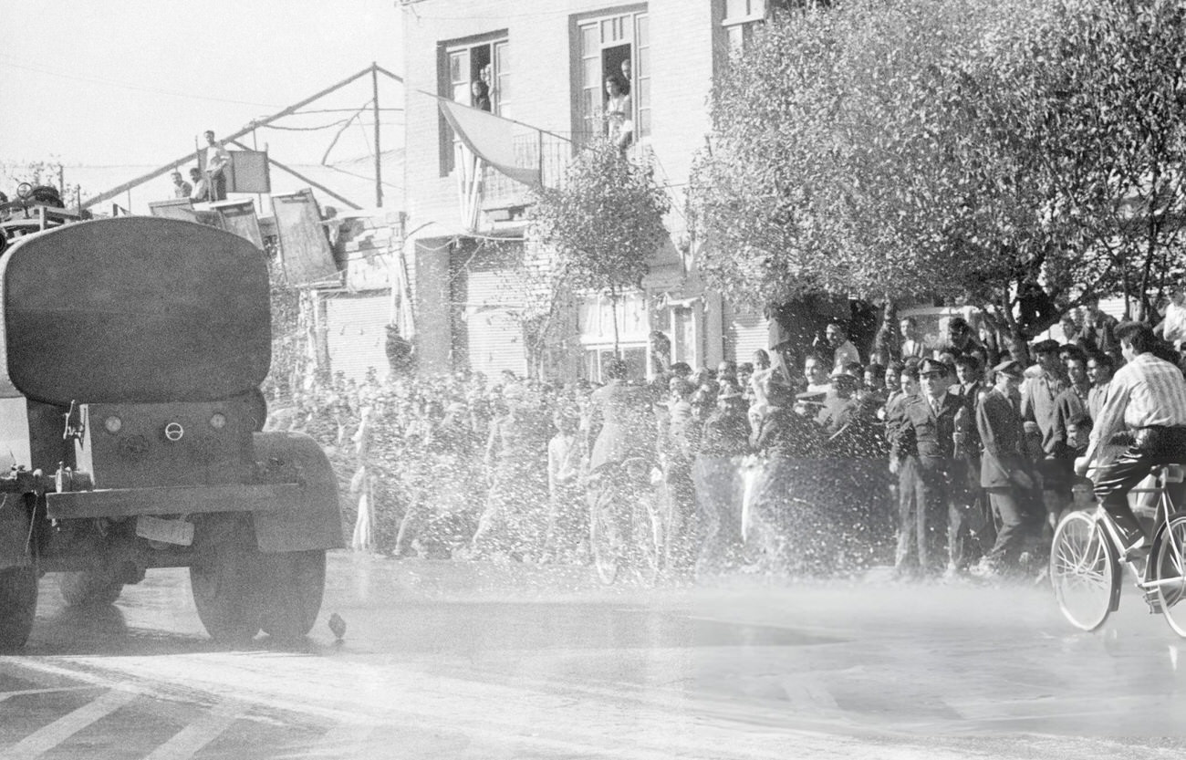 A joyous crowd being sprayed with water jets to clear the way for the Shah on his way to the maternity hospital for the birth of Prince Reza Cyrus Pahlavi, Tehran, 1960.