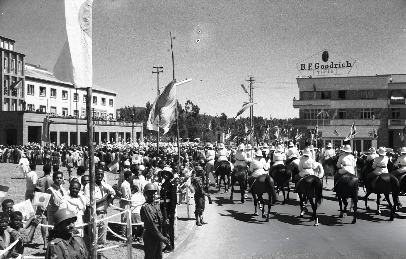 Horseback soldiers leading cars carrying Crown Prince Akihito and Crown Princess Michiko under an arch where a drawing of Crown Princess Michiko is hung on the way to the Guenete Leul Palace, Addis Abeba, 1960.