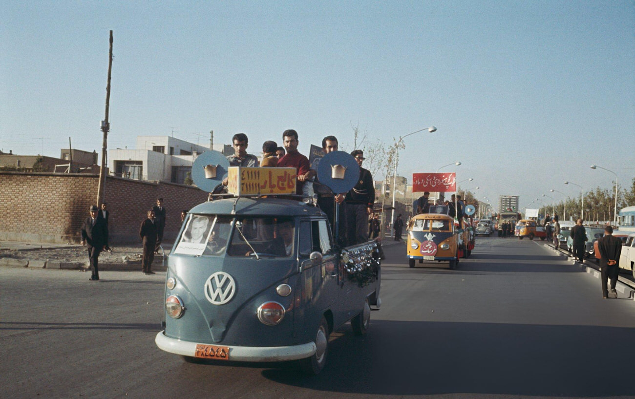 Residents and supporters of the Iranian monarchy being driven in Volkswagen Type 2 kombi vans along a main road in Tehran prior to the coronation of Mohammad Reza Pahlavi, 1967.