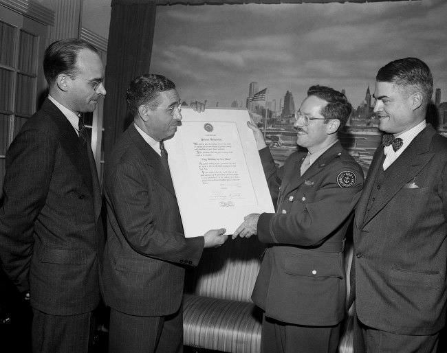 Joe Rosenthal, Associated Press staff photographer, receives a scroll from Joe Costa on behalf of the Press Photographers Association of New York in a ceremony commending him for his photo of the flag raising on Iwo Jima, in New York, 1945.