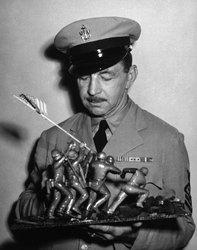 AP photographer Joe Rosenthal, holds a wood carving depicting his famous photo of the flag raising at Iwo Jima, 1945.