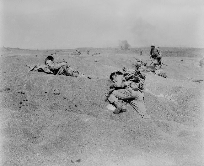 Two U.S. Marines, slumped in death, lie where they fell on Iwo Jima, among the first victims of Japanese gunfire as the American conquest of the strategic Japanese Volcano Island begins, 1945.