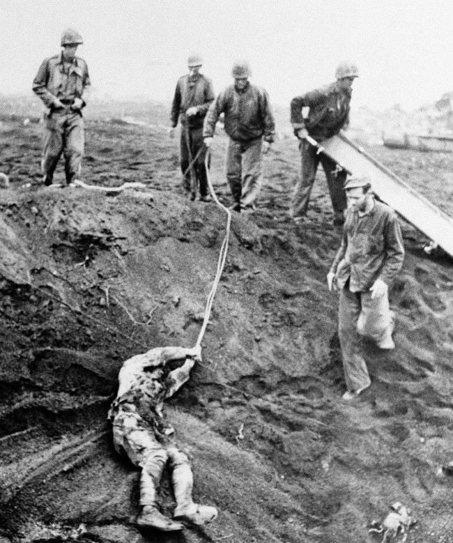 The first Japanese prisoner to be taken on Iwo Jima, Japan, is dragged from shell hole, 1945.