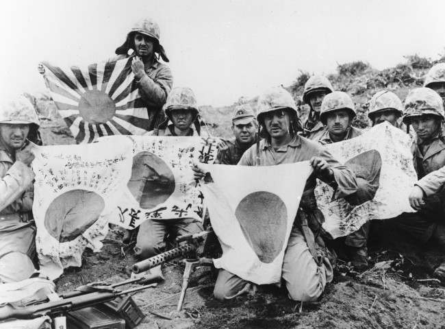 U.S. Marines of the 5th Division pose with captured Japanese battle flags, at Iwo Jima, 1945.