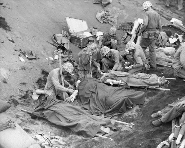 U.S. Navy doctors and medical corpsmen treat wounded U.S. Marines at an aid station established in a gully on Iwo Jima in the Pacific, Japan, 1945.