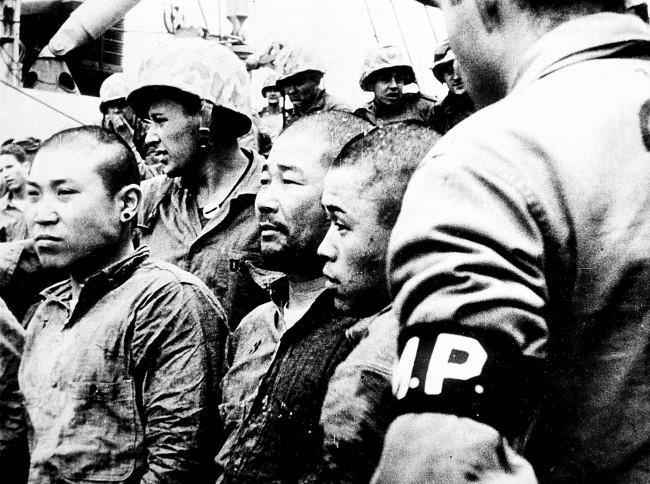 Three Japanese prisoners of war are shown aboard a U.S. Navy vessel in Japan, 1945.