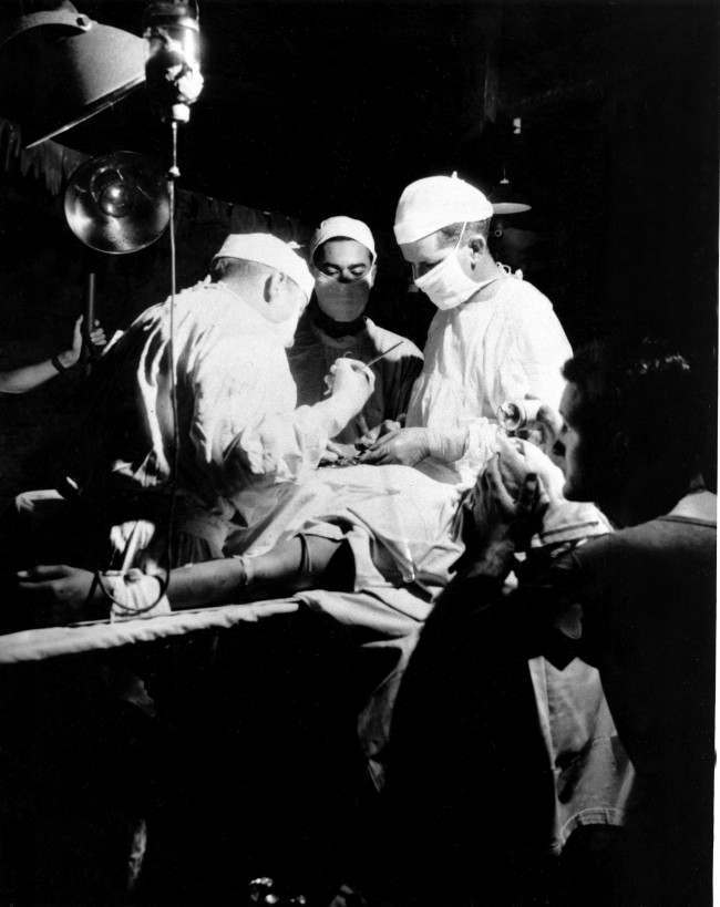 While a U.S. corpsman administers ether, Navy doctors operate to remove shrapnel from the abdomen of a wounded leatherneck at the Fourth Marine Division evacuation hospital in Iwo Jima, Japan, 1945.