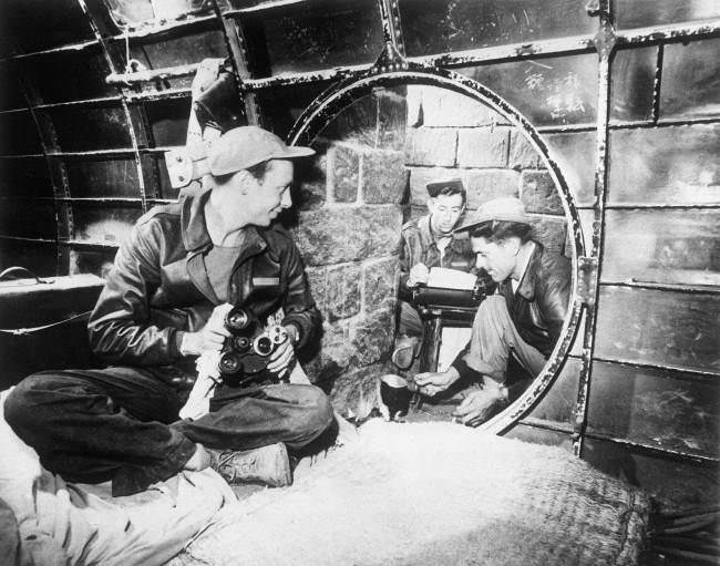 Twelve feet below the surface near an Iwo Jima airstrip, Japan, three 7th AAF combat cameramen establish their headquarters in a former Japanese underground quarters made of a wrecked bomber fuselage and stone blocks, 1945.