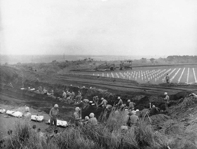 U.S. Marines dig graves in the Fifth Marine Division cemetery on Iwo Jima, Japan, for the shrouded bodies of their buddies, 1945.