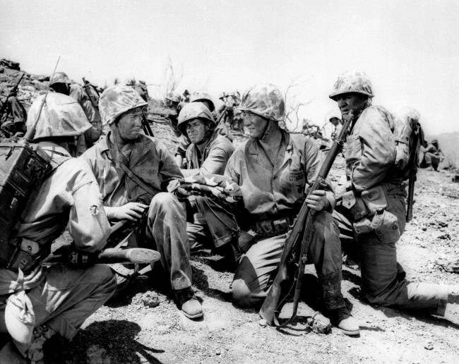 In the movie reproduction of the flag raising scene on Iwo Jima, Capt. H.G. Schrier, left, who actually carried the flag up Mt. Surabachi, hands the flag to John Wayne, 1975.